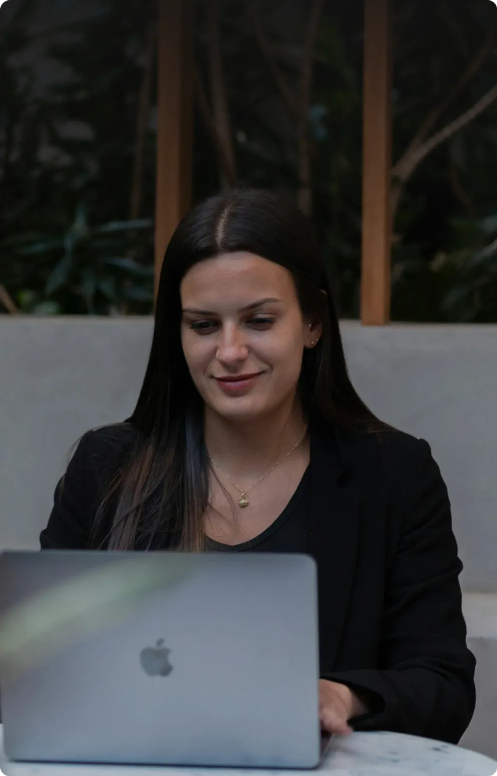 A woman smiling as she works on a laptop