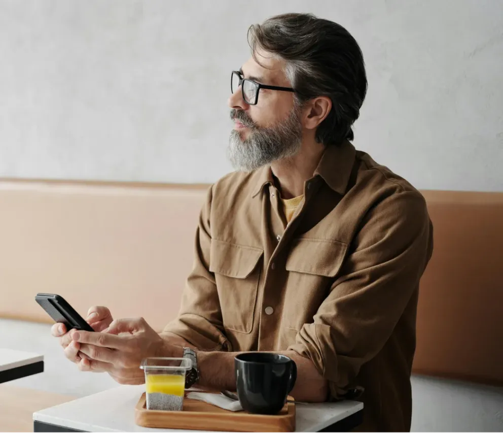 A founder checking his phone at a café table