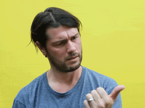 A man against a yellow wall frowns and starts counting off points on his fingers