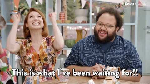 Two people at a table cheer, captioned this is what I've been waiting for