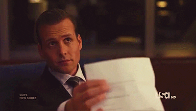 A man in a suit lowers a stack of papers and raises an eyebrow, unconvinced