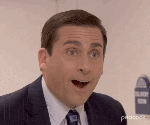 A man in a suit reacts with wide-eyed surprise