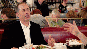 Two people talking over a meal in a diner booth, one gesturing mid-sentence