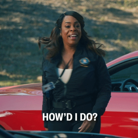 A woman beside a car turns to camera asking how she did